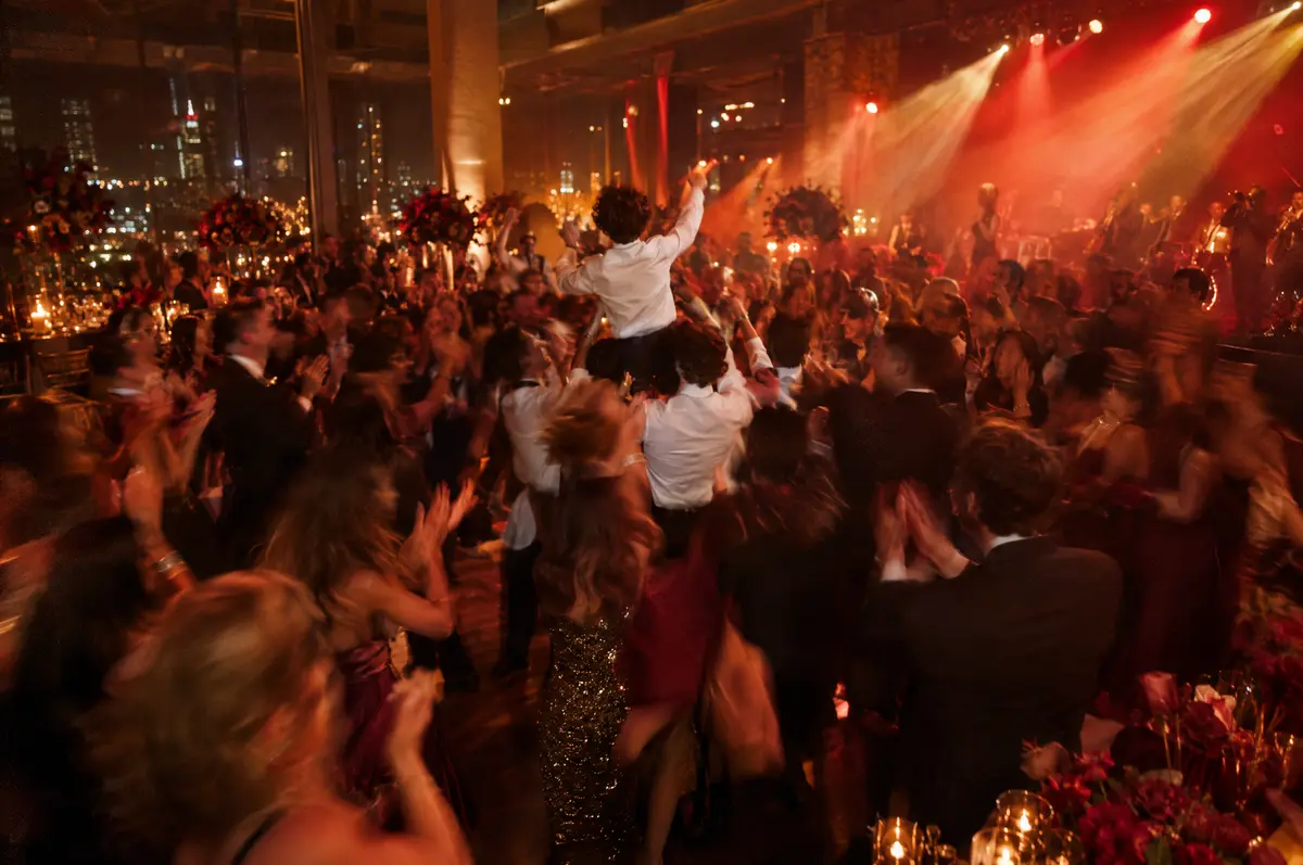 Guests dancing the hora in a circle under warm stage lights at a family celebration